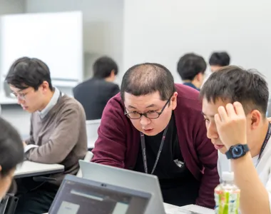 新人研修でパソコン画面を見ながら教え合う社員たち